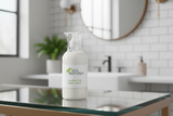 16 oz plastic clear bottle with white plastic lid with white lotion and label with Lux Natures logo with small green leaf and Coconut Milk Vegan Lotion, bottle stand on clear glass top in clean modern bathroom on background 